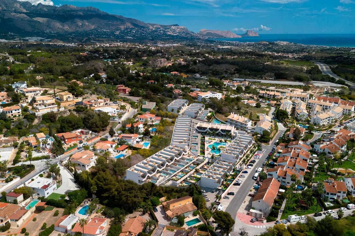 Luchtfoto van Alfas del Pi met het appartementcomplex te midden van de woonwijk en bergen.