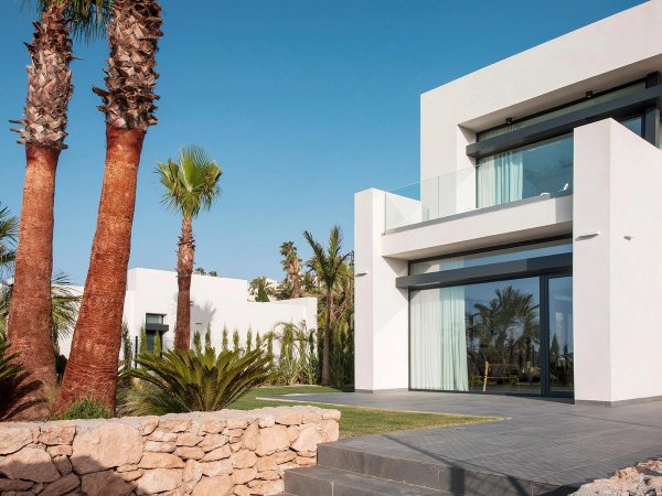 Moderne 4-slaapkamer villa exterieur met palm bomen en stenen muur in La Manga Club, Costa Calida, Spanje.