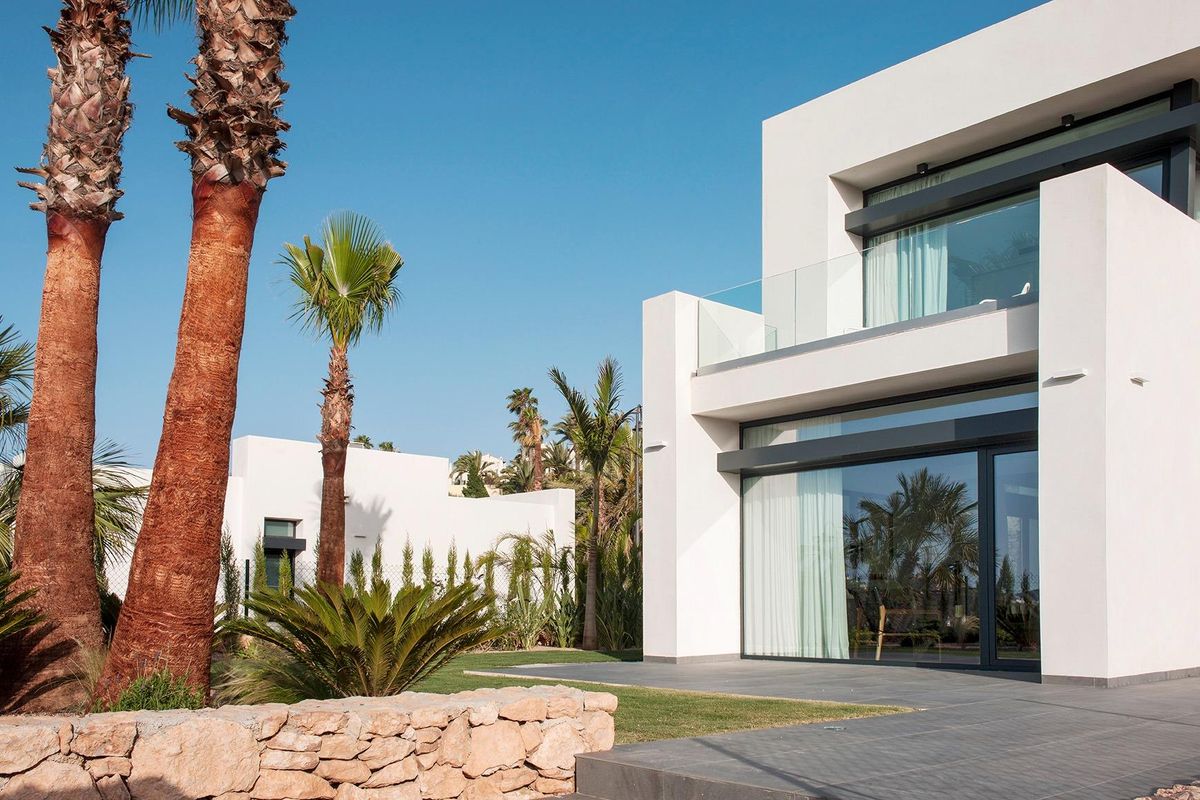 Moderne 4-slaapkamer villa exterieur met palm bomen en stenen muur in La Manga Club, Costa Calida, Spanje.