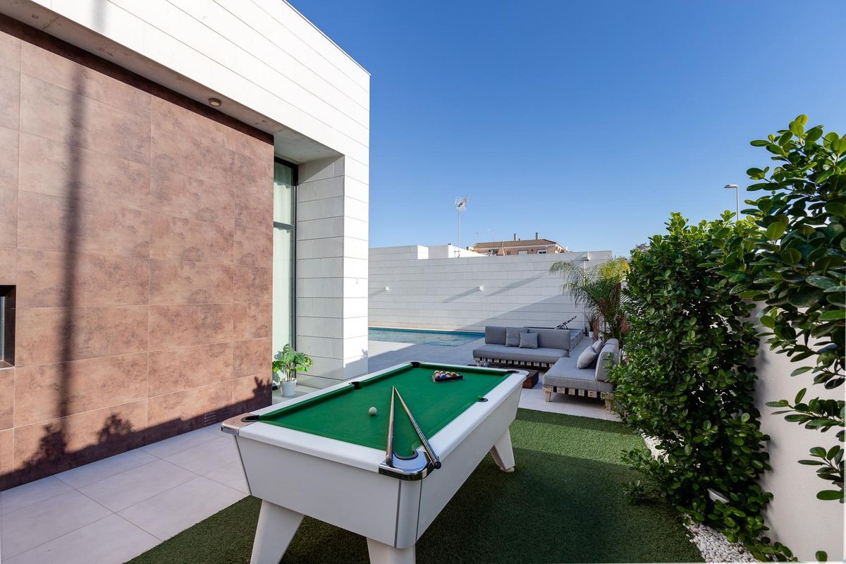 Buitenentertainmentruimte met een biljarttafel en planten nabij het zwembad in Pilar de La Horadada, Spanje.