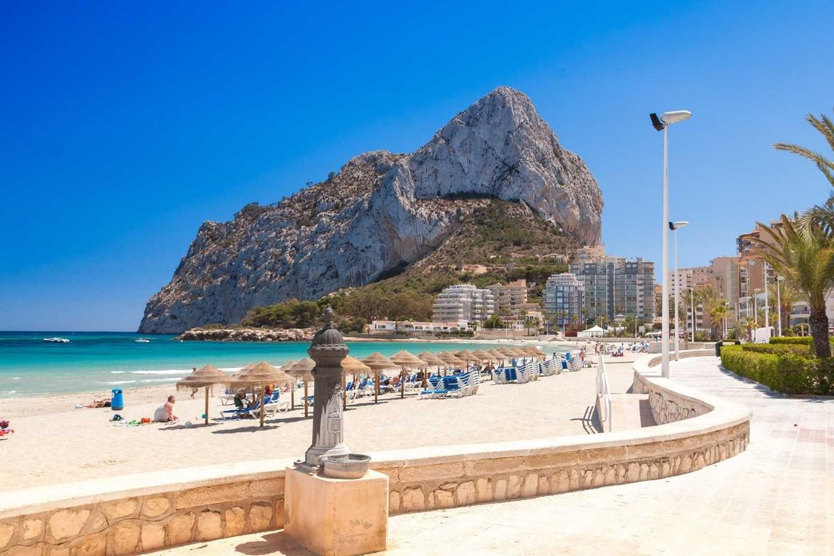 Stranden van Calpe, zandige kusten met ligbedden en een prachtige rotsachtergrond in Costa Blanca Noord.