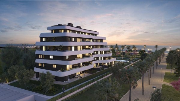 Modern appartementengebouw tijdens zonsondergang in Torremolinos, Costa del Sol, met groene omgeving.