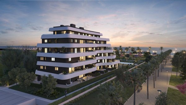 Modern appartementengebouw tijdens zonsondergang in Torremolinos, Costa del Sol, met groene omgeving.