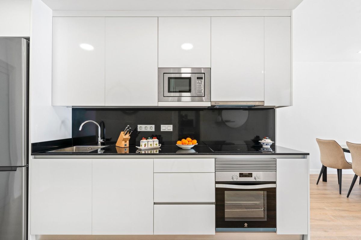 Moderne keuken met strakke witte kasten en zwarte werkbladen in een penthouse in Orihuela Costa.