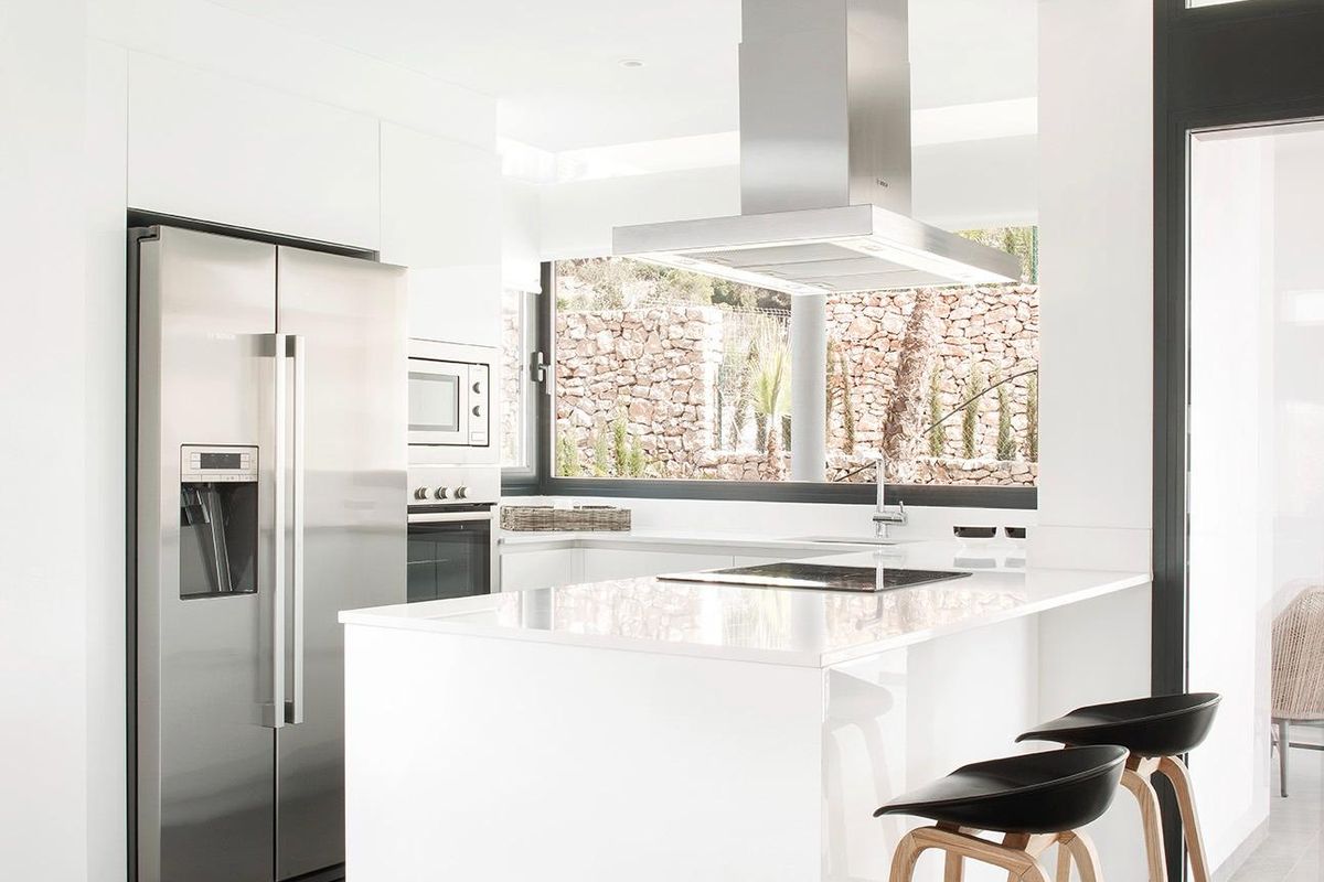 Strakke keuken met moderne apparaten en grote ramen die natuurlijk licht binnenlaten in villa in La Manga.