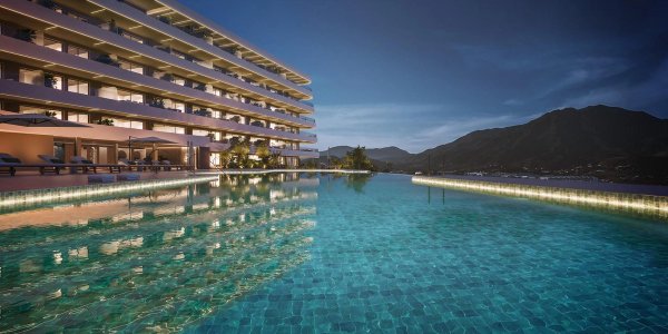 Avondzicht op het luxe zwembad dat het gebouw weerspiegelt, gelegen in Estepona, Costa del Sol, Spanje.