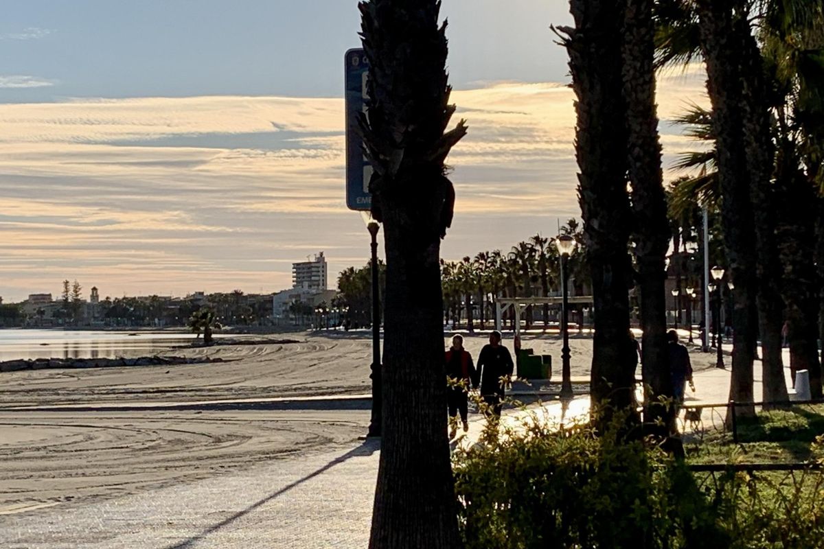 Vroeg in de ochtend scène langs de promenade met wandelaars en palmbomen in Los Alcazares.