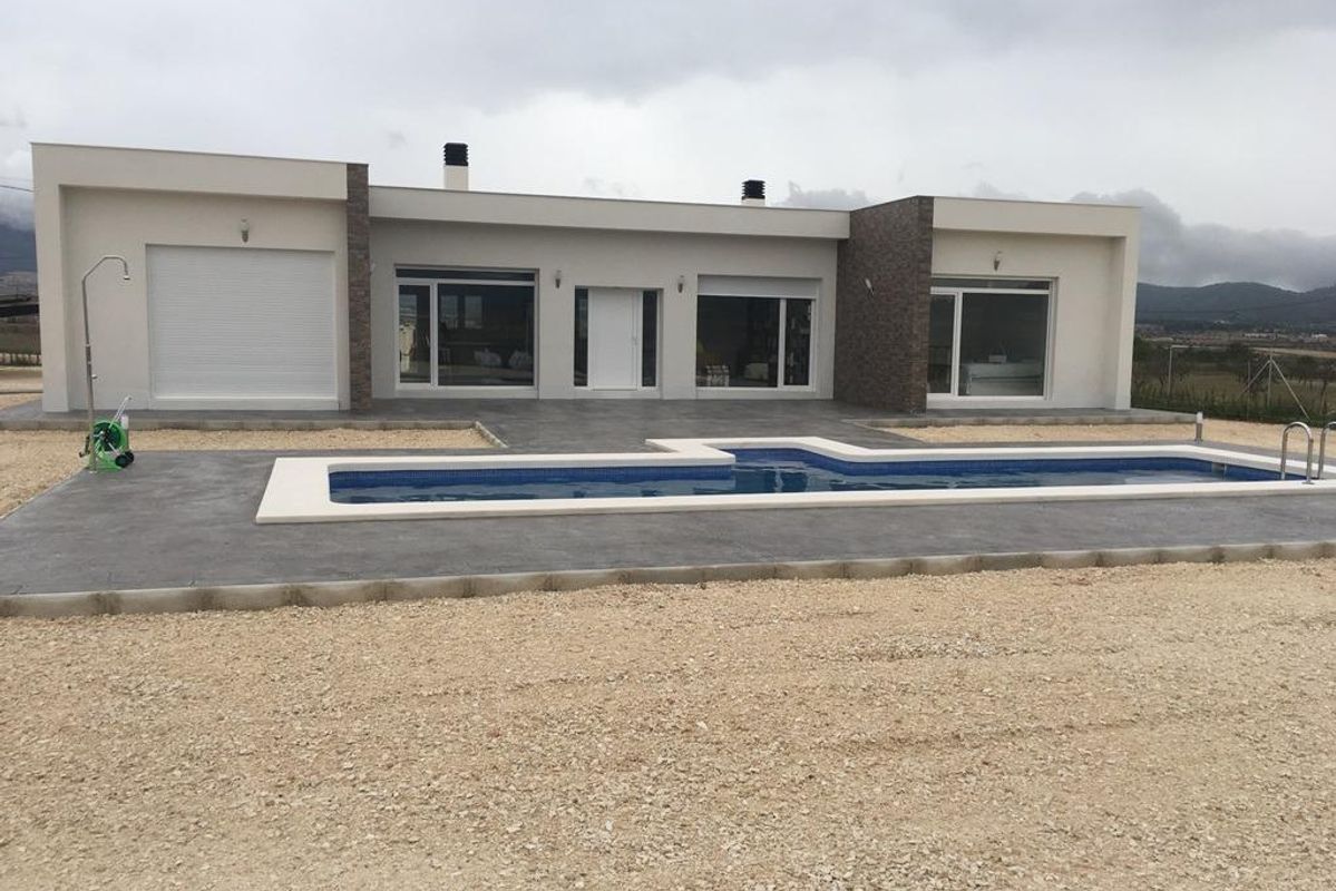 Vooraanzicht van een stijlvolle villa met 3 slaapkamers en een zwembad in Pinoso, Costa Blanca South, vastgelegd op een bewolkte dag.