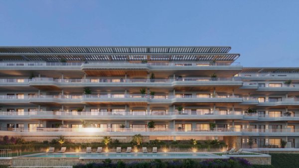 Buitenzijde van een modern appartement van 2 slaapkamers in Torremolinos, met meerdere terrassen en avondverlichting.