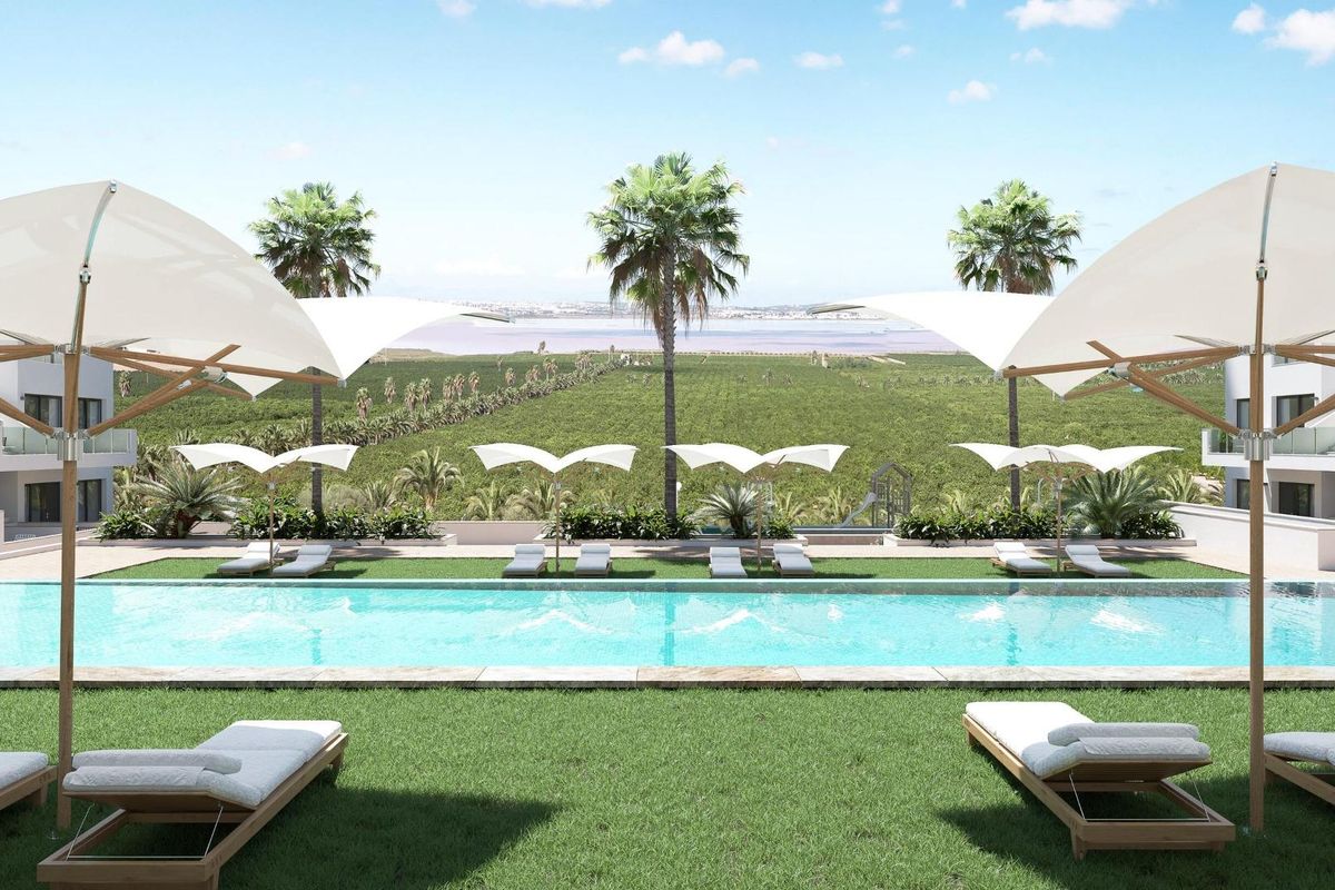 Idyllisch zwembaduitzicht vanaf het gazon met parasols op de voorgrond in Torrevieja, Costa Blanca Zuid.