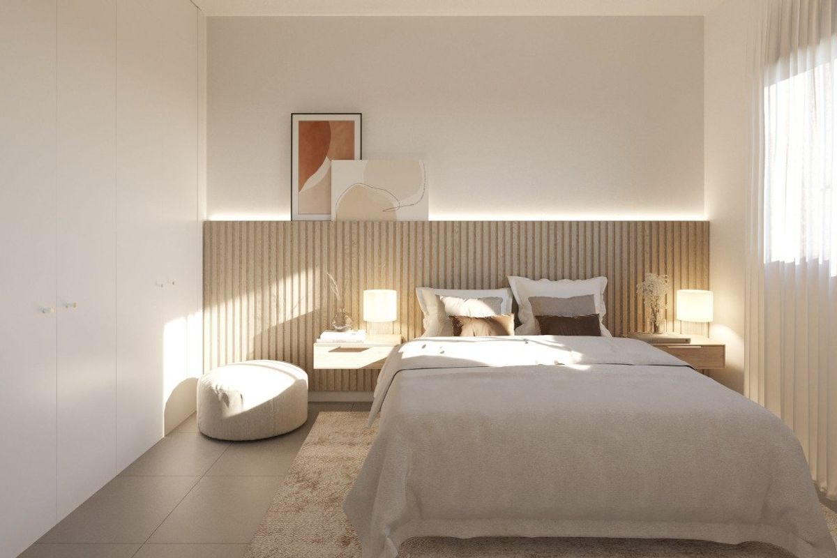 Sunlit bedroom in a Manilva townhouse with contemporary furnishings, sleek built-in wardrobe, and soft neutral tones.