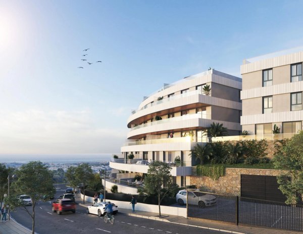 Buitenzijde van een modern 2-slaapkamer appartementengebouw in Estepona, met balkons en weelderige begroeiing.