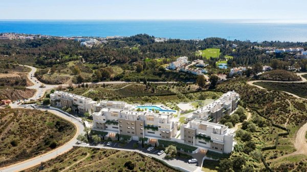Luchtfoto van een modern appartementencomplex in Mijas, Costa del Sol, met weelderig landschap en de zee.
