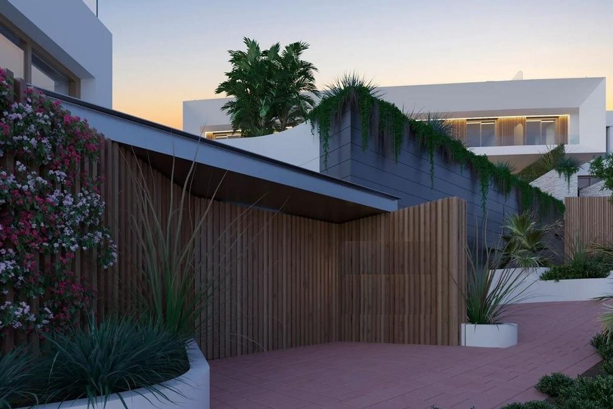 Buitenkant van een moderne townhouse met tuinen en bloeiende planten in Estepona, Costa del Sol.