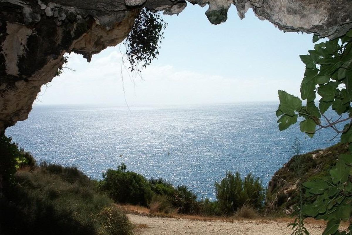 Uitzicht vanuit een grotingang over de sprankelende zee, die de natuurlijke schoonheid nabij Benitachell, Costa Blanca Noord, laat zien.