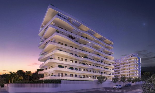 Modern 3-slaapkamer appartement gebouw in Villajoyosa, Costa Blanca, verlicht bij schemering met stijlvolle architectuur.