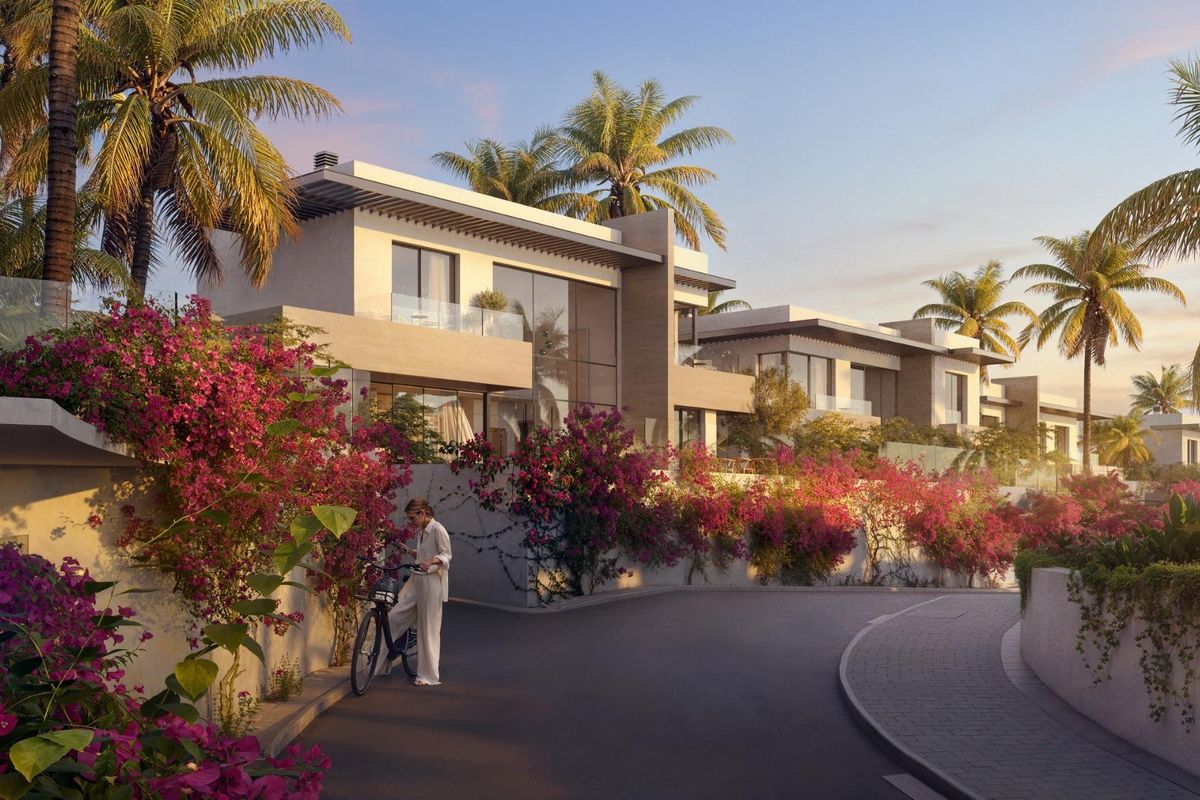 Mooie ingang naar een moderne villa in Mijas, omringd door kleurrijke bloemen en palmbomen.