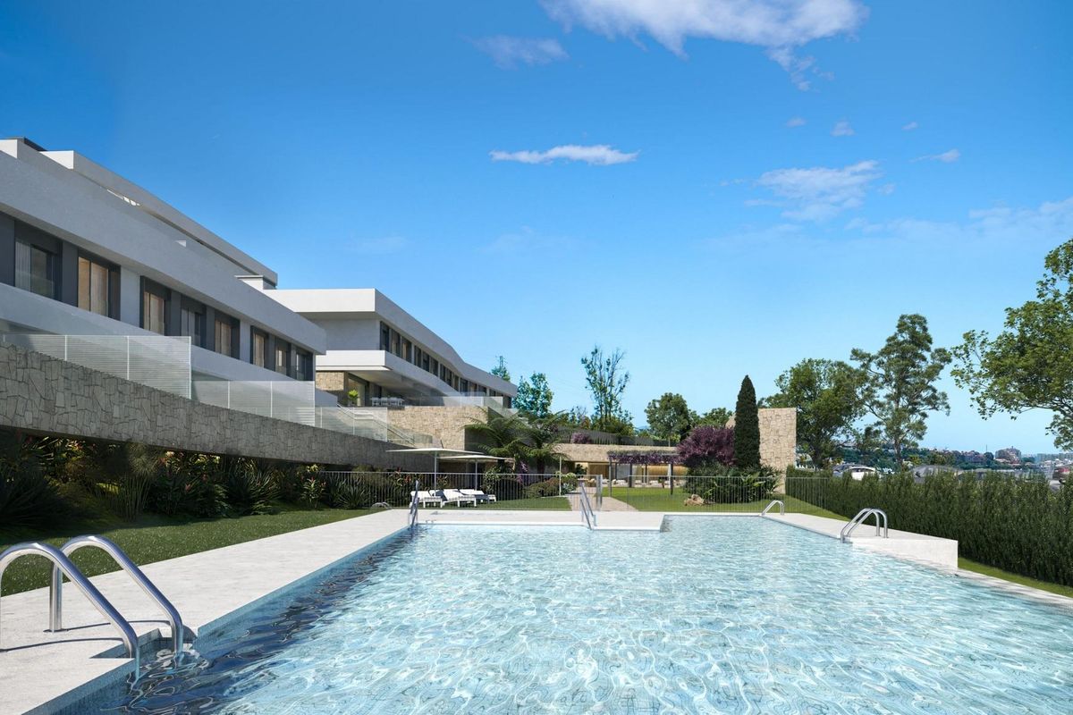 Aantrekkelijk zwembad in het appartementencomplex in Estepona, omgeven door groen en ligstoelen.