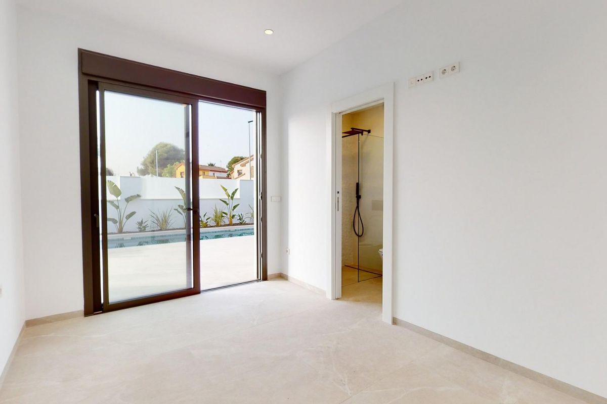 Heldere slaapkamer met schuifdeuren die naar een terras leiden in een moderne villa in Costa Calida.