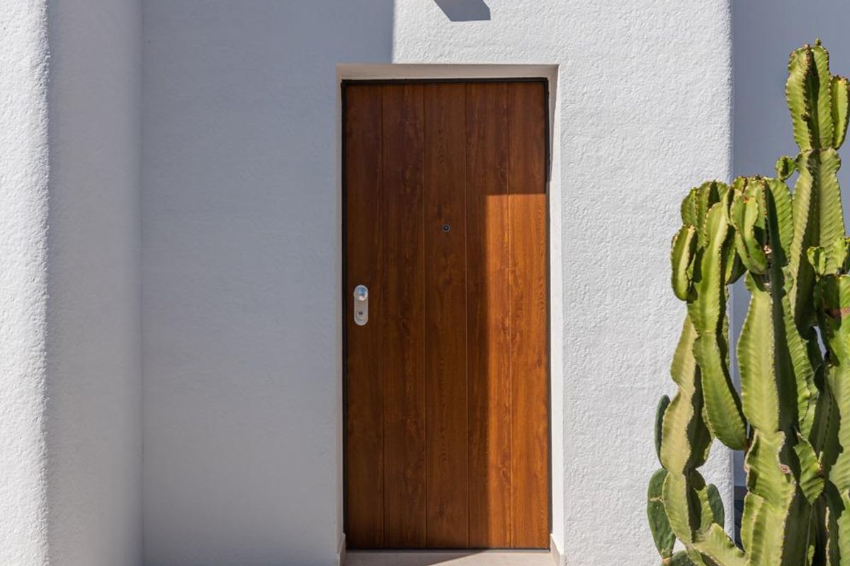 Entree van de villa met een houten deur en een aangelegde pad, gelegen in Los Alcazares.