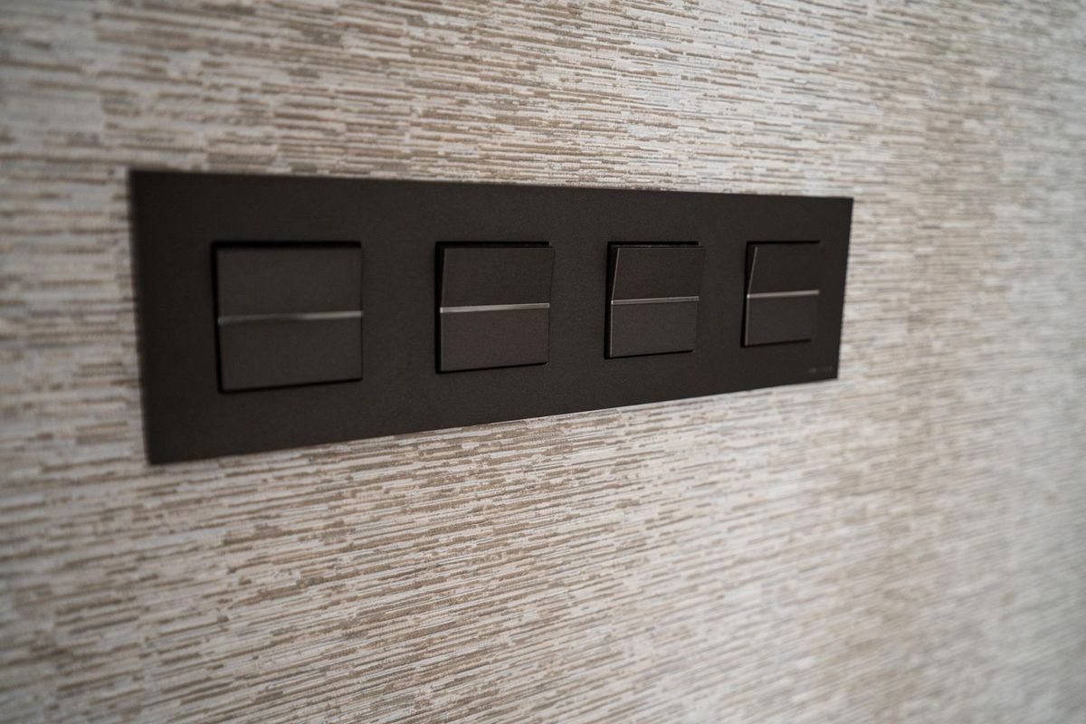 Moderne lichtschakelaars op een textuurwand in een hedendaagse 3-slaapkamer bungalow gelegen in Pilar de La Horadada, Spanje.