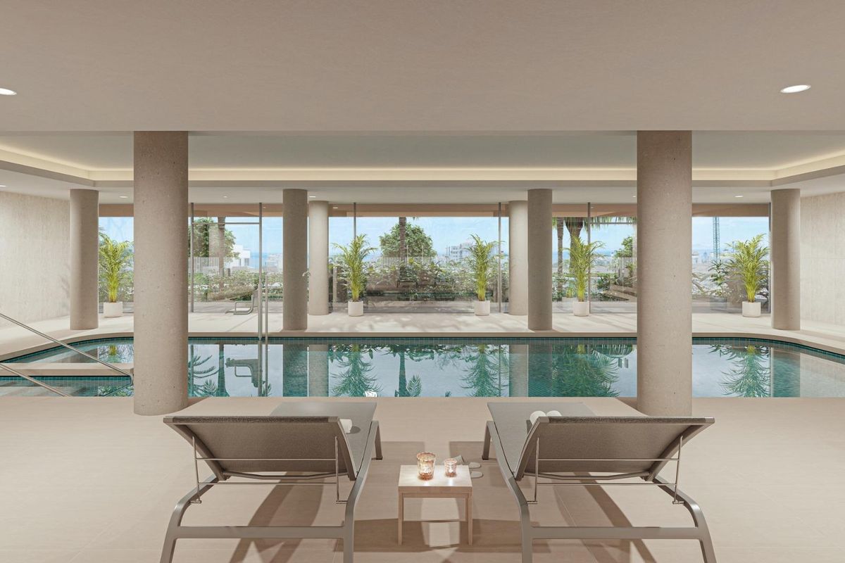 Binnenzwembad met ligstoelen en grote ramen in het appartementcomplex in Estepona.
