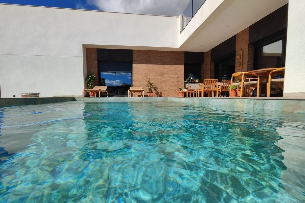Crystal-clear pool reflecting the villa in Pinoso, showcasing modern architecture and outdoor space.