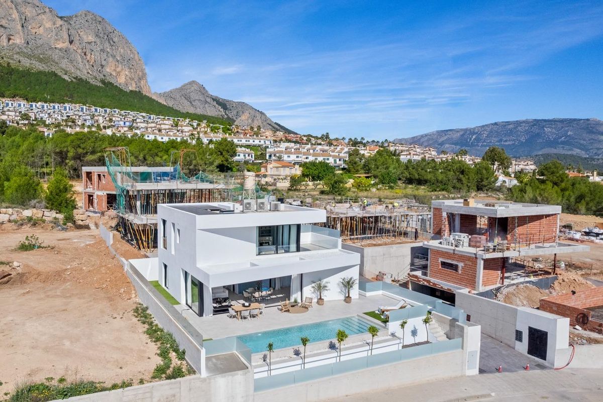 Luchtfoto van een moderne villa in Polop met zwembad en omliggende bouwactiviteiten.