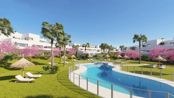 Exterieur van een 3-slaapkamer penthouse complex in Estepona met een kronkelend zwembad, ligstoelen, palmbomen en roze bloeiende bomen.