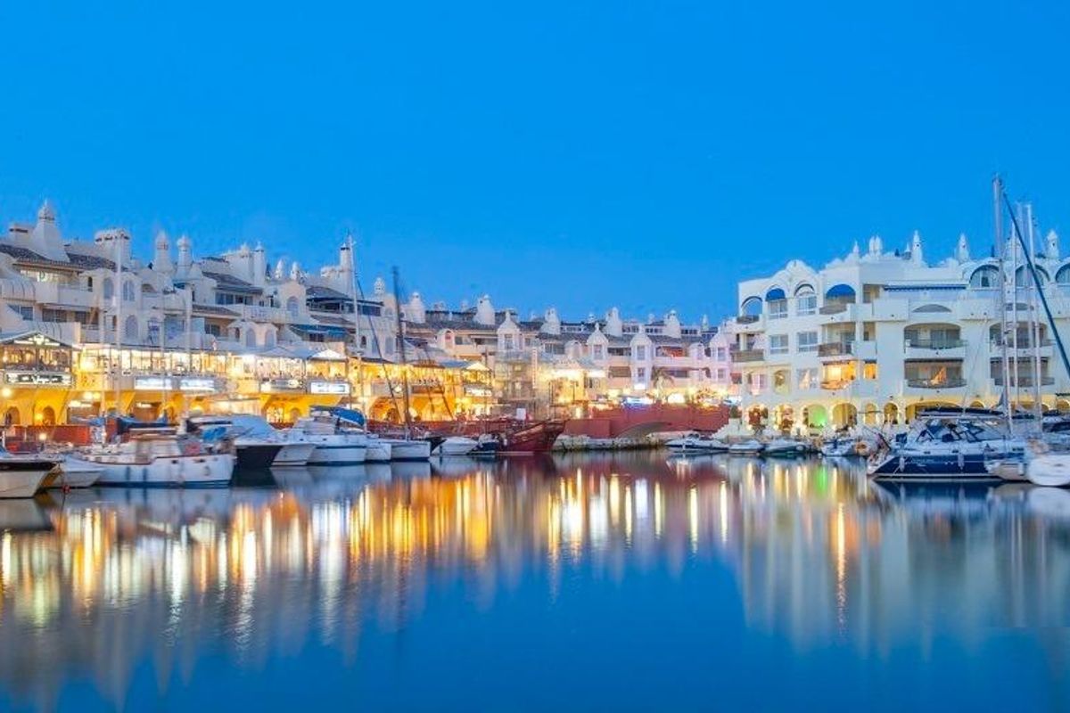 Nachtzicht op een jachthaven vol boten, die lichten in het water weerkaatsen in Torremolinos, Costa del Sol.