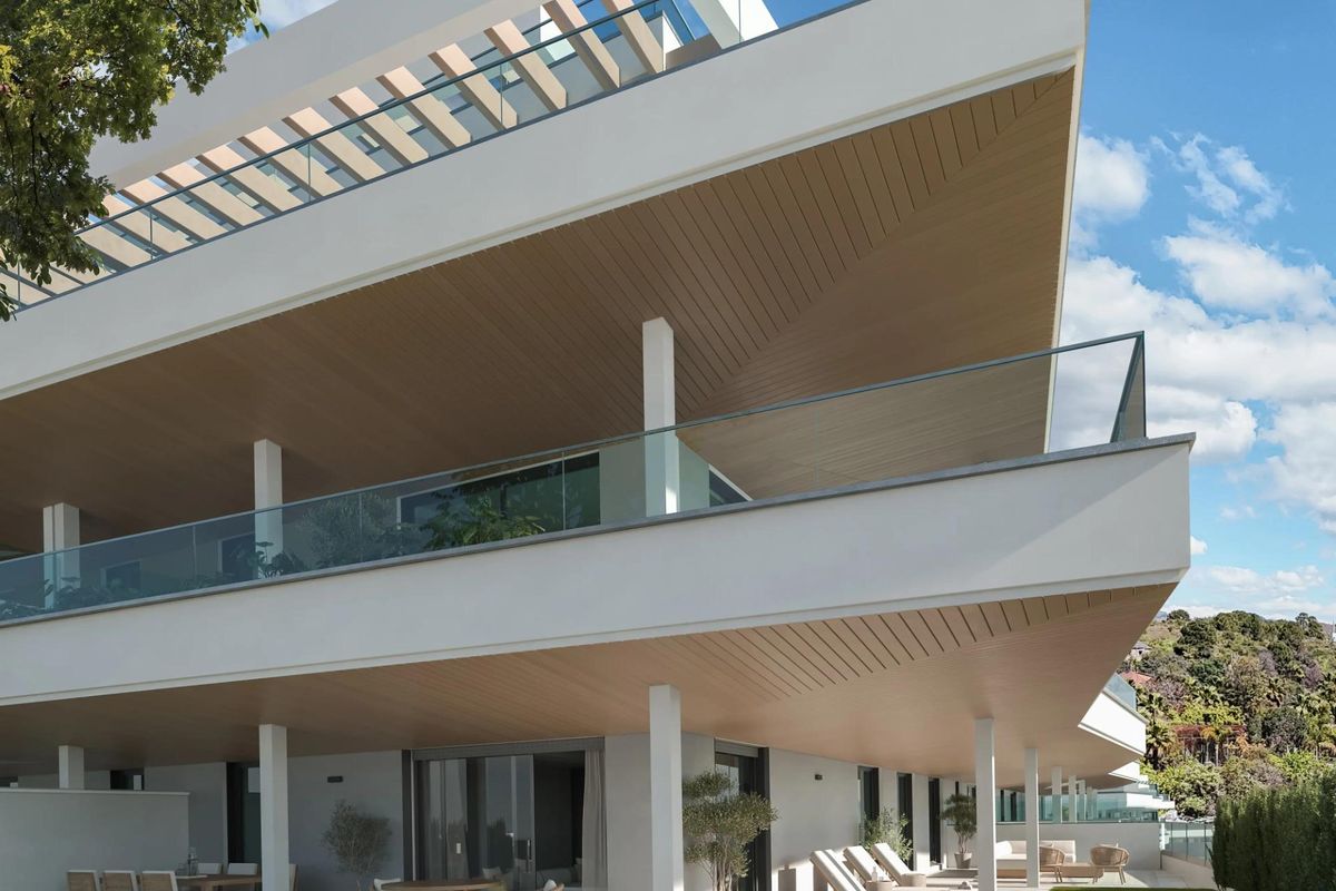 Moderne buitenaanzicht van een nieuw appartementencomplex in Estepona, met ruime terrassen en groen.