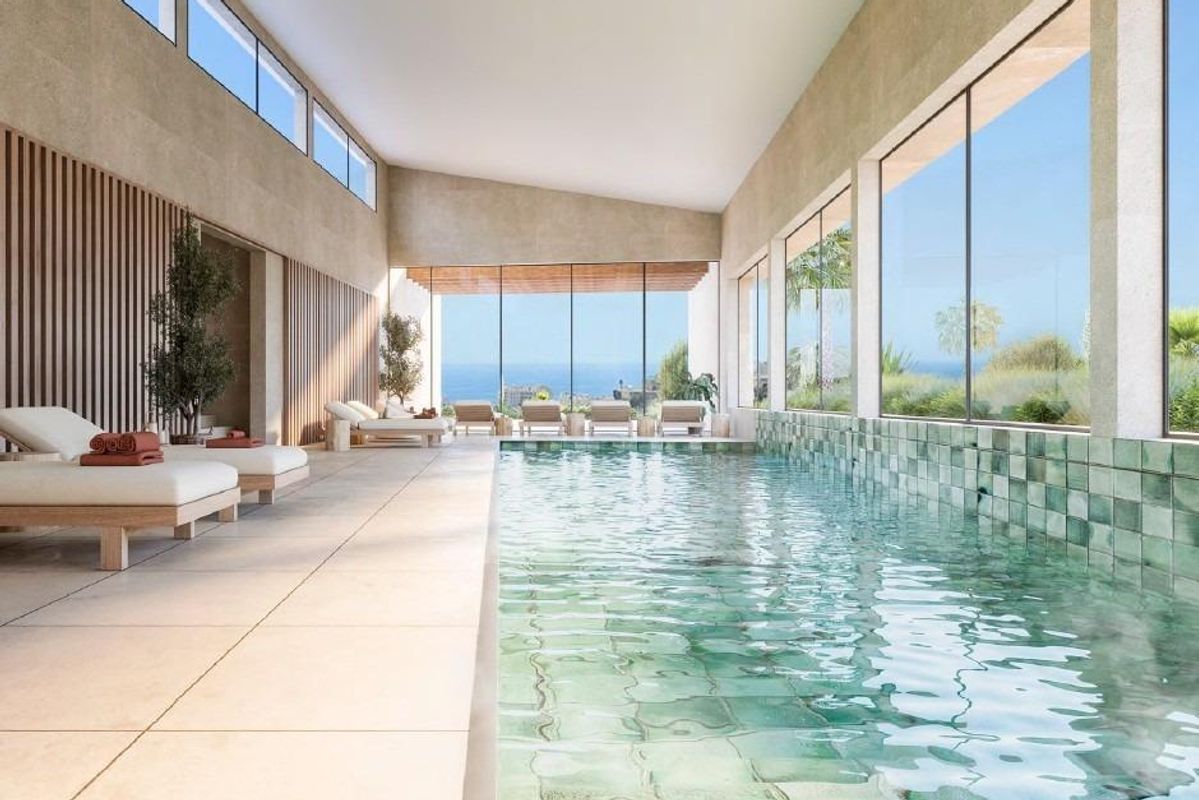 Heldere binnenzwembad met panoramische ramen, met uitzicht op de omliggende tuinen in de Costa del Sol.