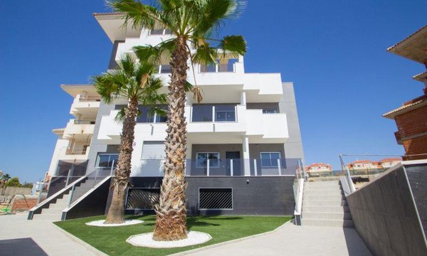 Buitenkant van een modern appartementencomplex met palmbomen in Orihuela Costa, Spanje.