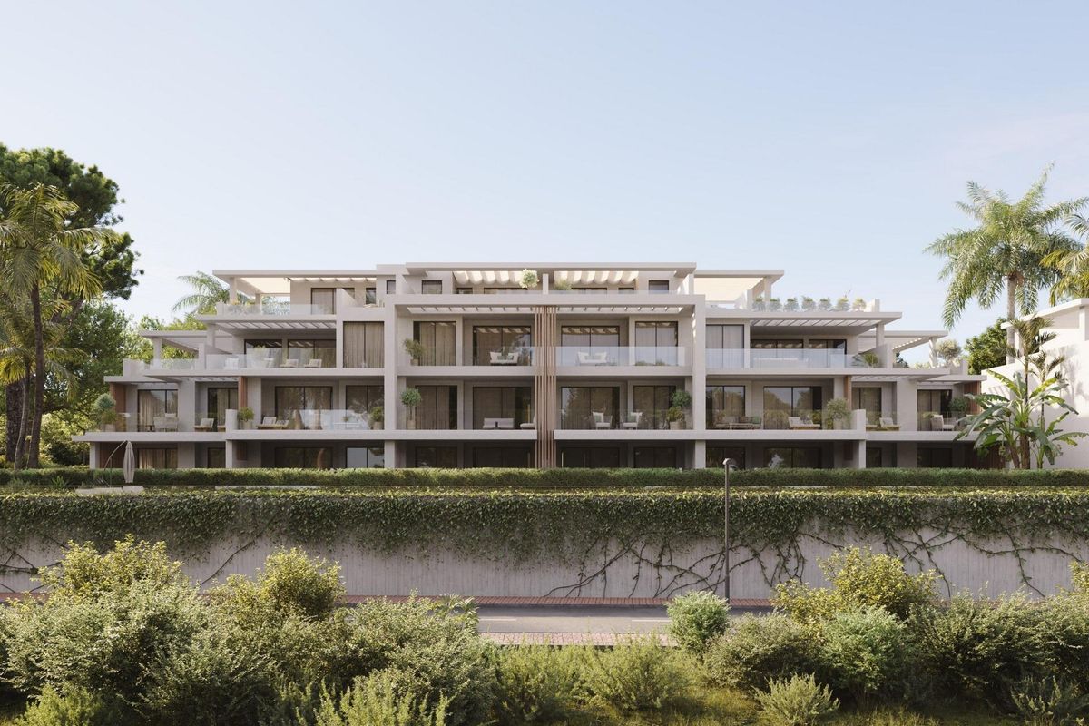 Vooraanzicht van een levendig penthousegebouw in Estepona, met balcons en weelderige tuinen.
