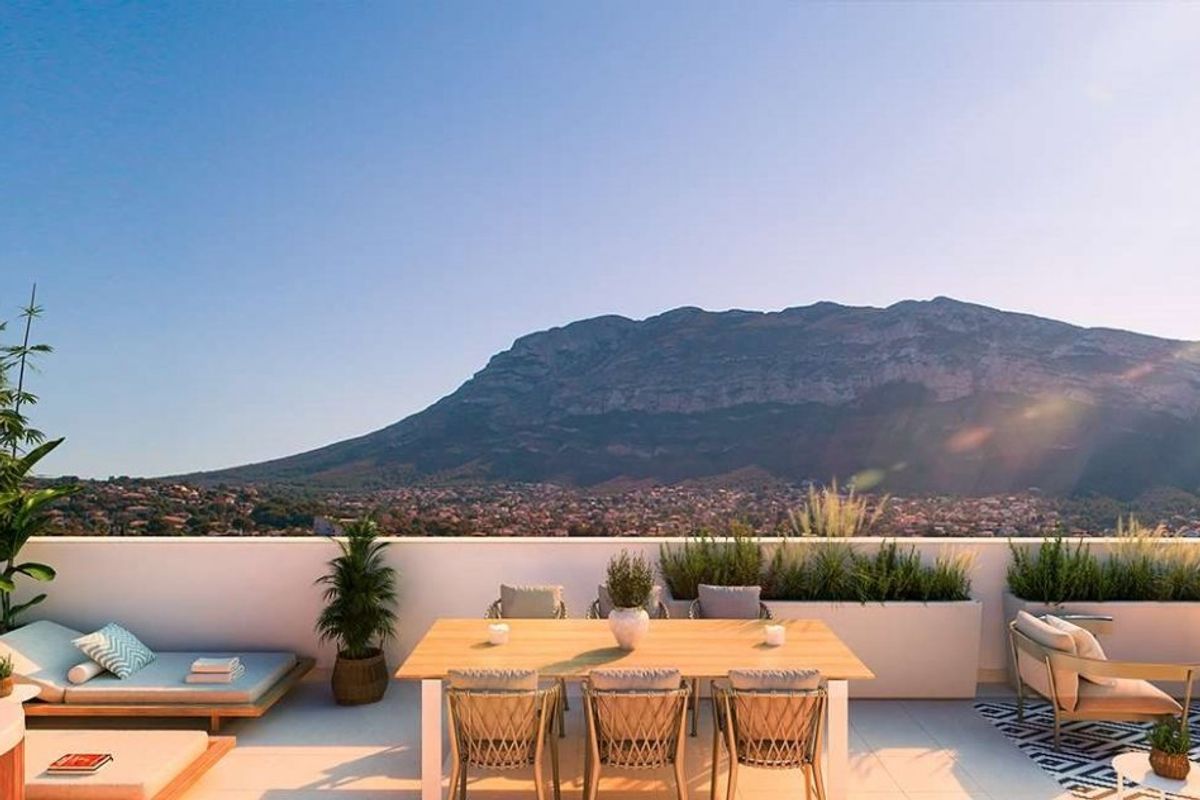 Prachtig terras van een penthouse in Denia, met panoramisch uitzicht op de bergen en een gezellige eetopstelling.