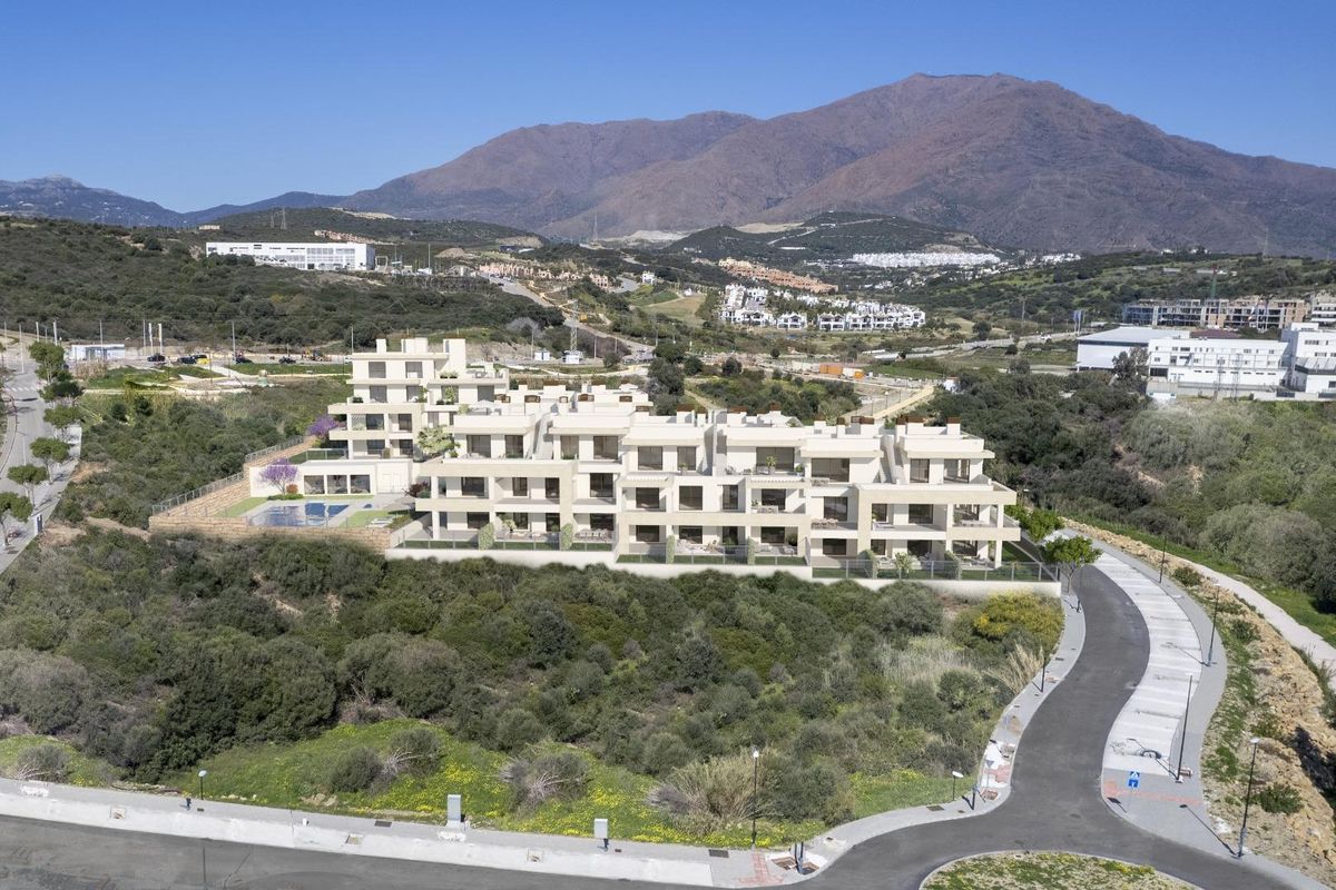 Indrukwekkende luchtfoto van penthouses in Estepona tegen een bergachtergrond, toont moderne architectuur.