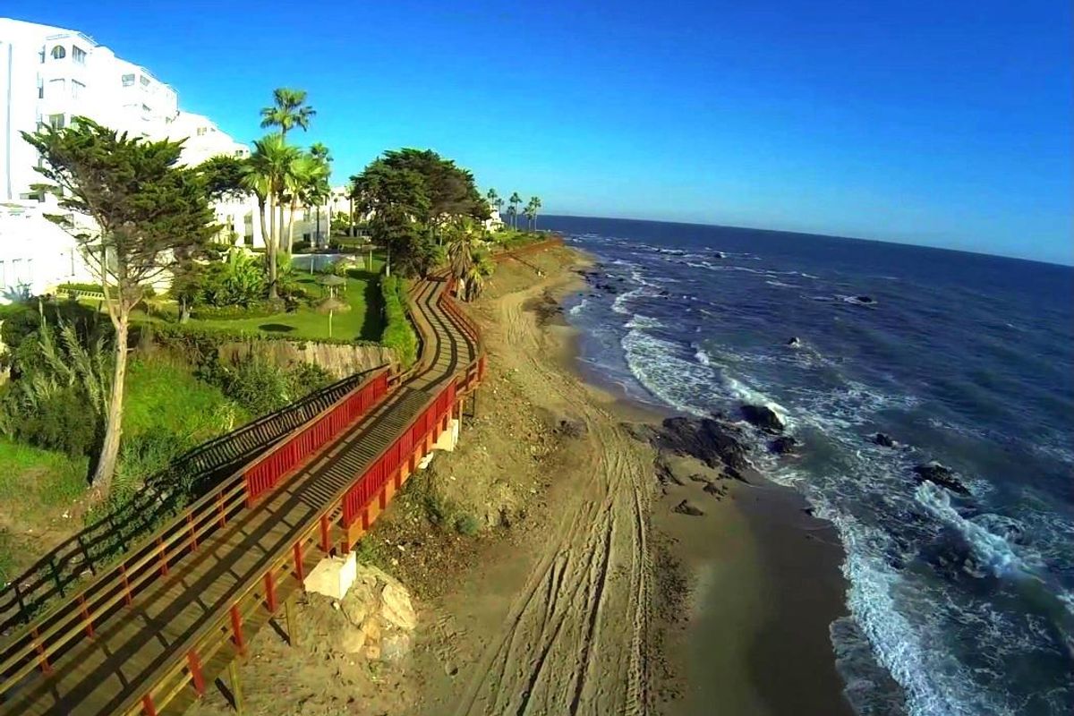 Prachtig uitzicht op de kust nabij Mijas met een zandstrand en palmbomen op de achtergrond.