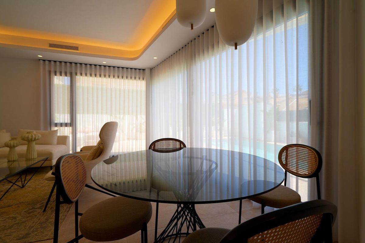 Stijlvolle eetruimte met een glazen tafel en zachte gordijnen in een 3-slaapkamer villa, Orihuela Costa, Spanje.