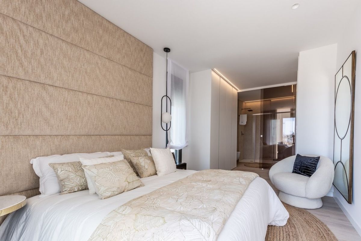 Stylishly decorated bedroom in a 4-bed villa in Finestrat, Spain. Features double bed, textured wall and modern bathroom beyond.
