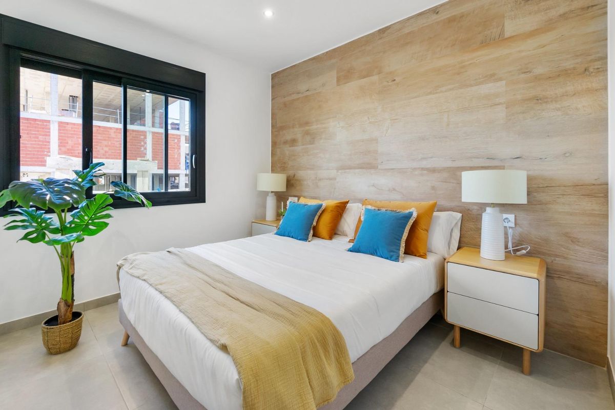 Heldere slaapkamer met houten accenten en een queensize bed in een modern appartement in San Javier.