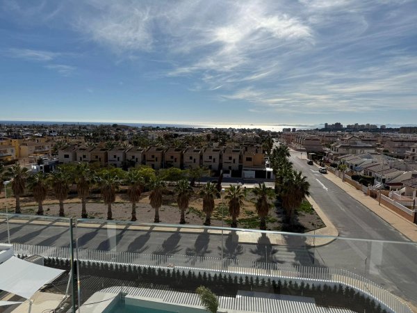 Uitzicht vanaf penthouse in Orihuela Costa met palmbomen en kustwoningen.