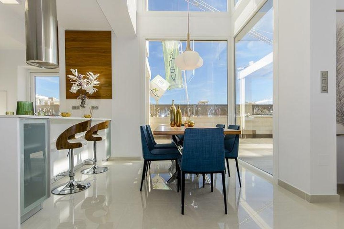 Stijlvolle eetruimte met blauwe stoelen en tafel, natuurlijk licht van grote ramen in villa in Rojales.