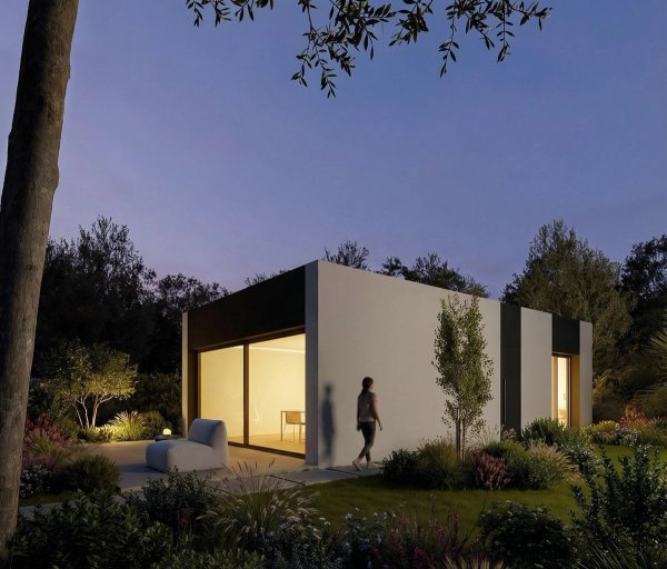 Exterior dusk view of a modern 2-bed villa in Alfas del Pi, Costa Blanca, with a woman walking towards the entrance.