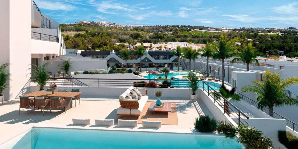 Een terrasje met uitzicht over het gemeenschappelijke zwembad en tuinen van een appartement op de begane grond in Alfas del Pi.