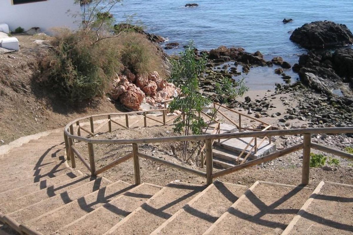 Kronkelige trap naar een rotsachtig strand met helder water, met schilderachtige uitzichten in Torremolinos, Costa del Sol.