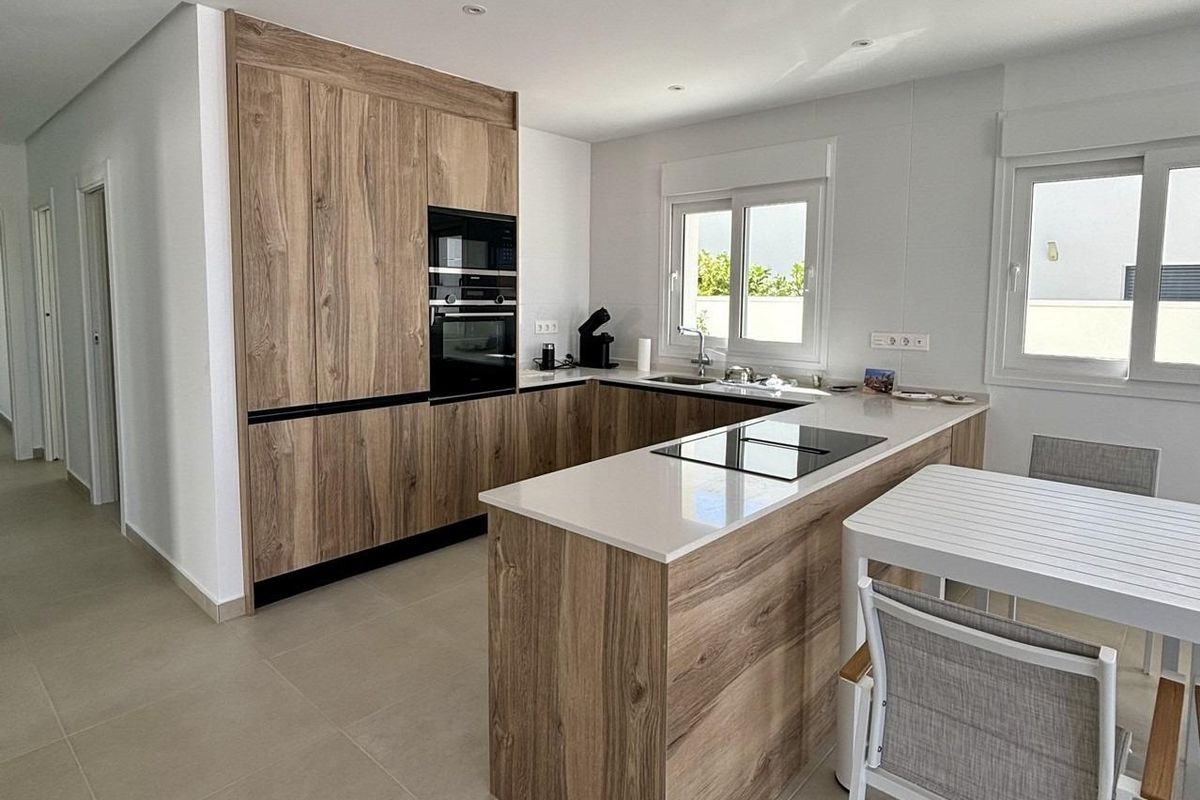 Strakke keuken met houten kasten en eetgedeelte in een 3-slaapkamer villa in Benijofar.