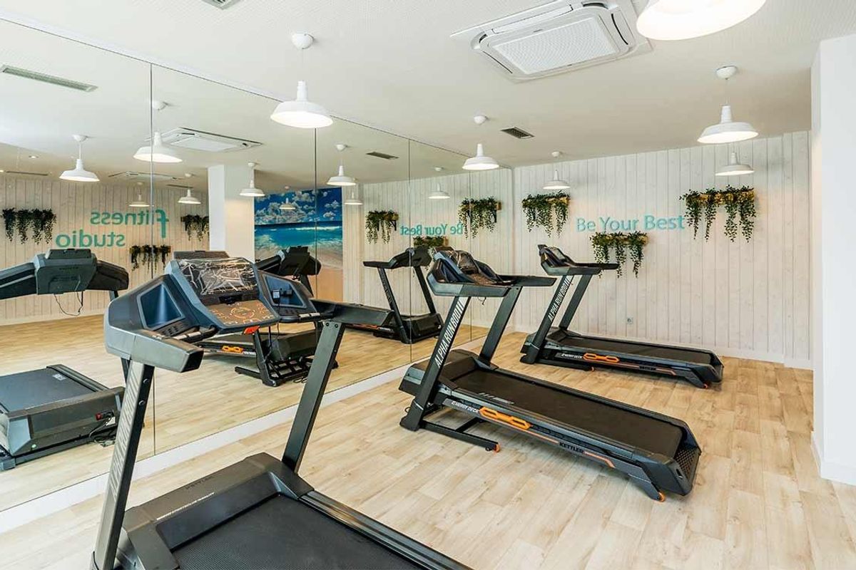 Goed uitgeruste fitnessstudio in een woning in Benalmádena, met meerdere loopbanden en een strandachtergrond.