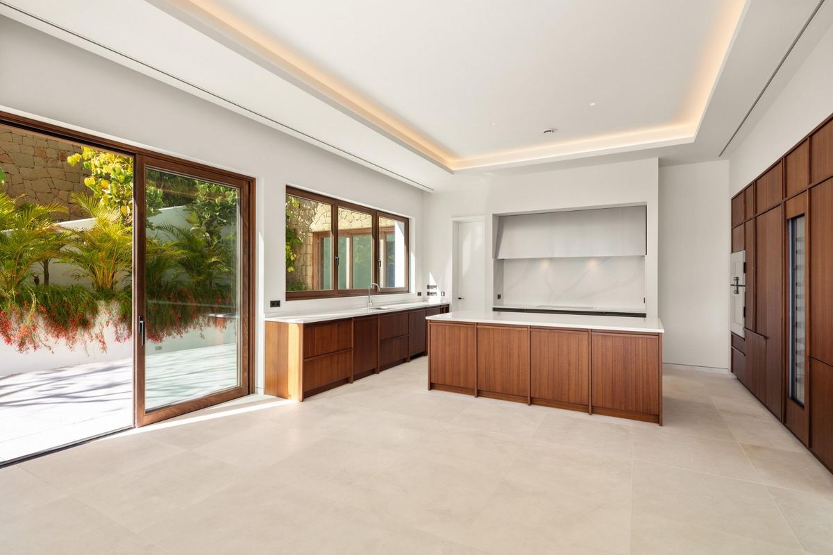 Stijlvolle keuken met houten kasten en grote ramen naar de buitenzijde in Casares, Costa del Sol.