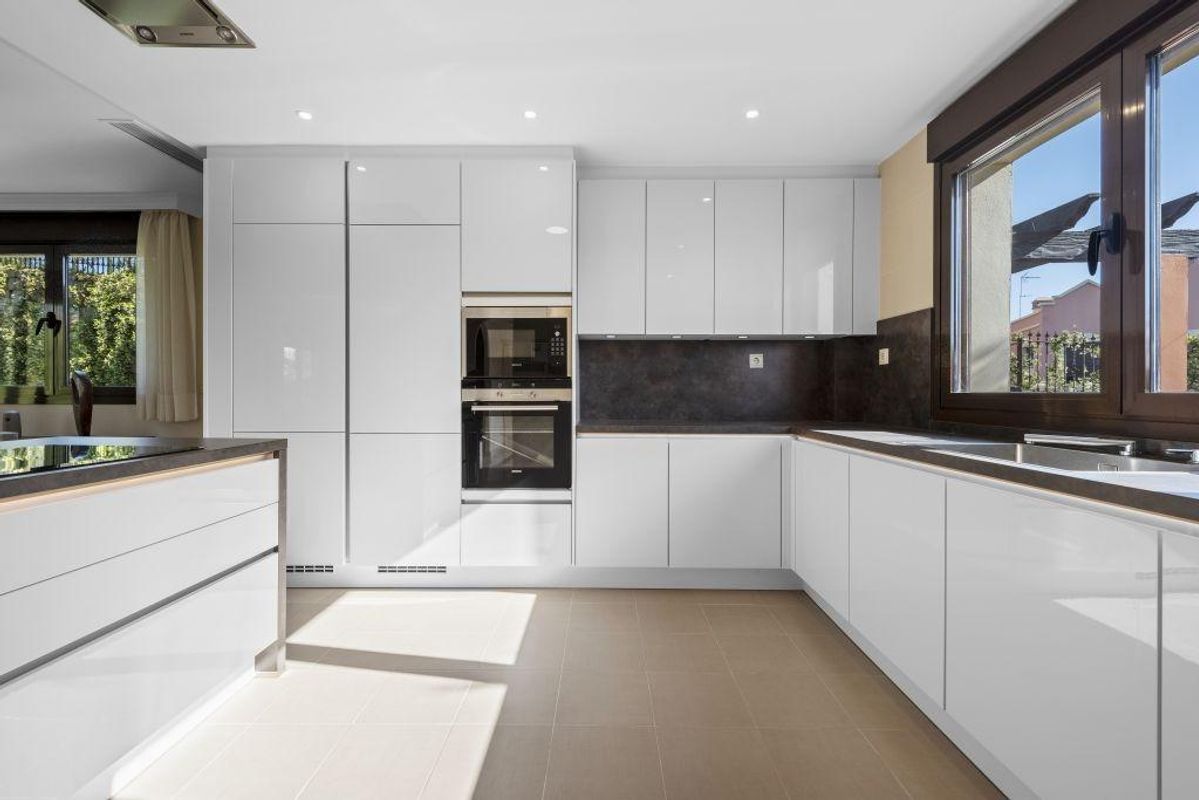 Stijlvolle keuken met witte kasten en een zonnig uitzicht vanuit de villa in Estepona, perfect om te koken.