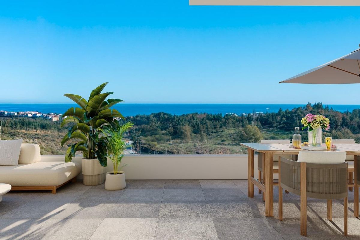 Zonnig terras van een appartement in Mijas met uitzicht op weelderige groene heuvels en de zee, ideaal voor buiten dineren.